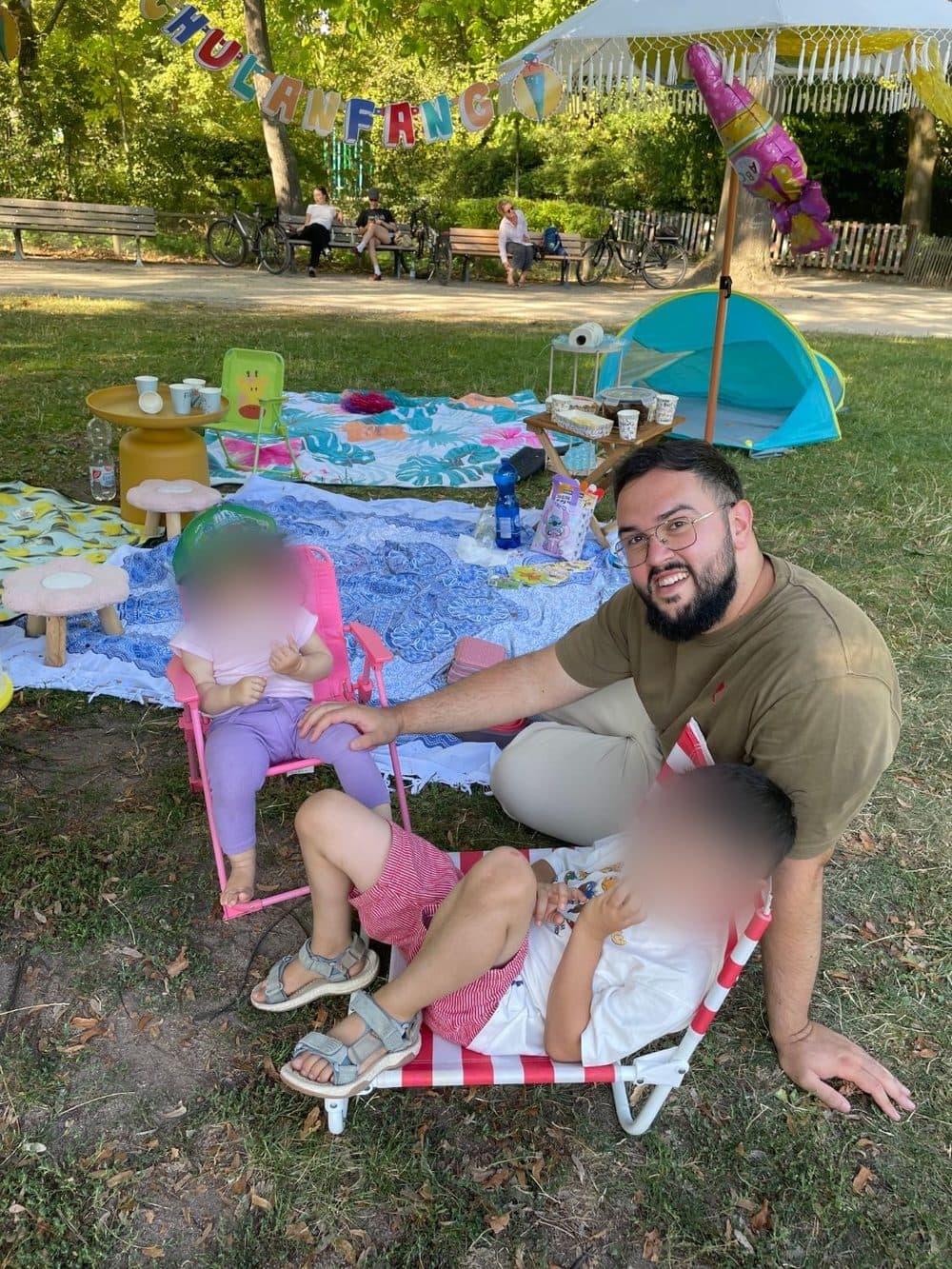 Muhammed bei einem Picknick mit seinen beiden Kindern, deren Gesichter unkenntlich gemacht sind